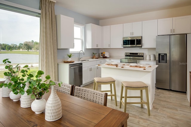 kitchen with white cabinets, sink, light wood-type flooring, and stainless steel appliances