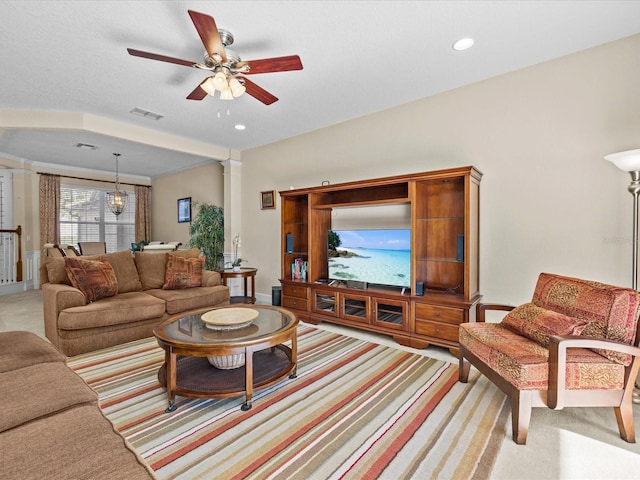 carpeted living room with decorative columns and ceiling fan