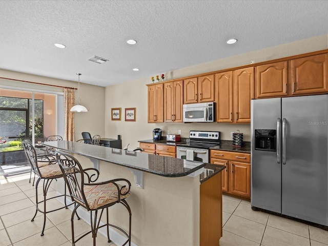 kitchen with a center island, pendant lighting, a breakfast bar area, light tile patterned floors, and appliances with stainless steel finishes