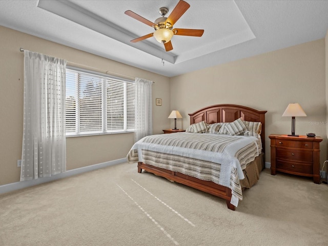 carpeted bedroom featuring a raised ceiling and ceiling fan