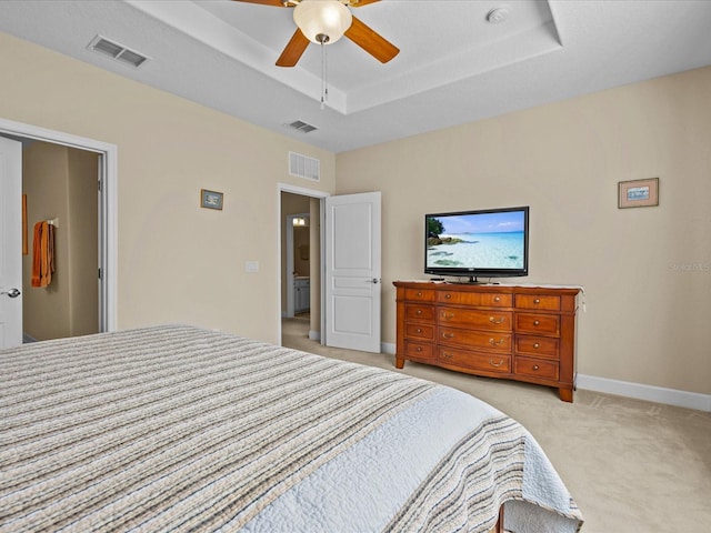 bedroom featuring light colored carpet, ceiling fan, and a tray ceiling