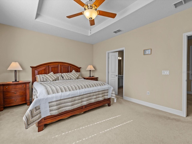 bedroom featuring ceiling fan, light colored carpet, and a tray ceiling