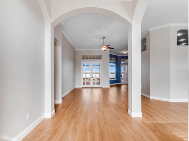 unfurnished living room with ceiling fan, french doors, ornamental molding, and light wood-type flooring