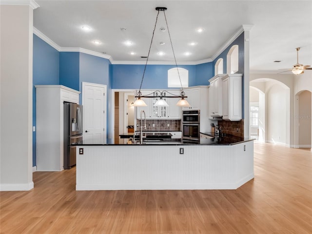 kitchen featuring light hardwood / wood-style floors, white cabinets, hanging light fixtures, and appliances with stainless steel finishes