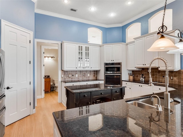 kitchen with dark stone countertops, sink, white cabinets, and hanging light fixtures