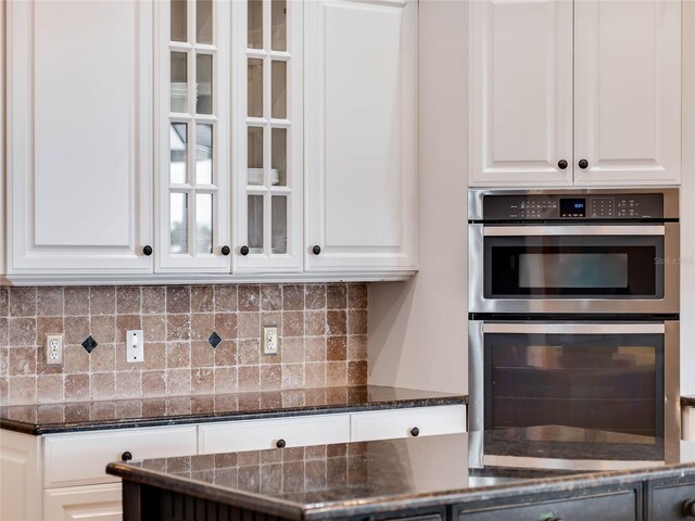 kitchen with white cabinetry, double oven, and dark stone counters