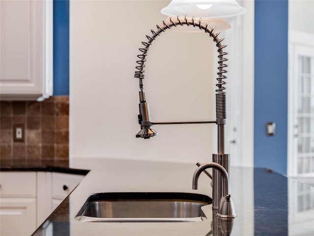 interior details featuring white cabinets, decorative backsplash, and sink