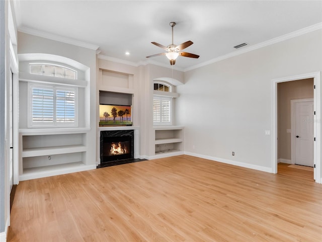 unfurnished living room featuring ceiling fan, crown molding, built in features, light hardwood / wood-style flooring, and a premium fireplace