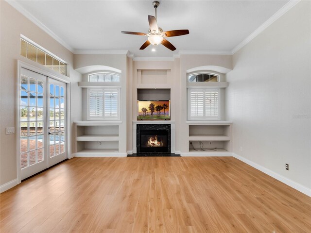 unfurnished living room featuring plenty of natural light, a premium fireplace, ornamental molding, and light hardwood / wood-style flooring