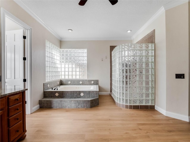 bathroom with tiled bath, crown molding, hardwood / wood-style floors, and a textured ceiling