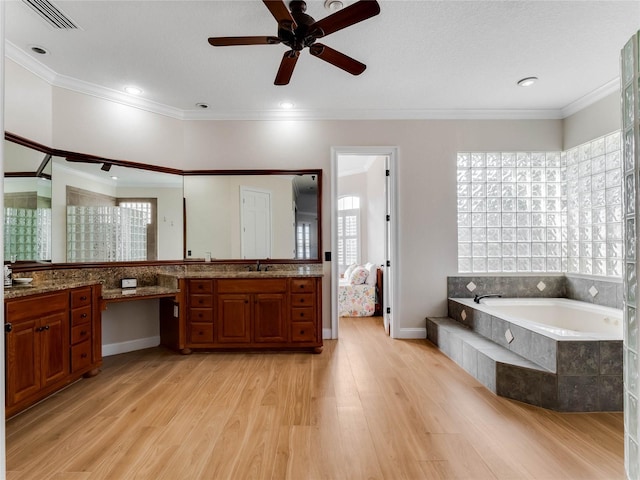 bathroom featuring plenty of natural light, wood-type flooring, crown molding, and tiled tub