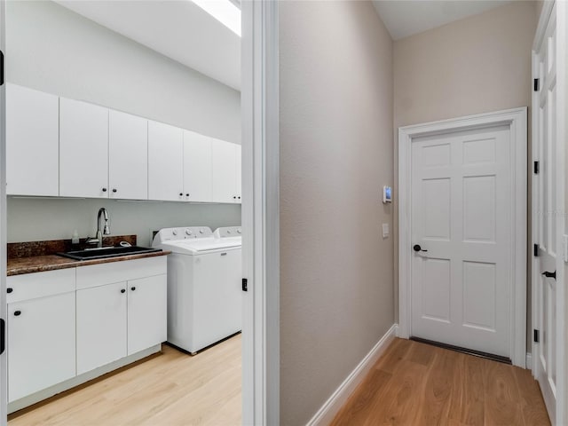 laundry area featuring washer and clothes dryer, sink, cabinets, and light wood-type flooring