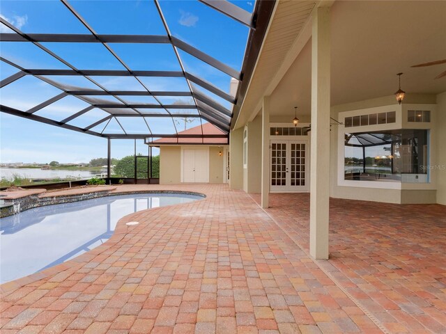 view of swimming pool featuring glass enclosure, a patio area, french doors, and a water view