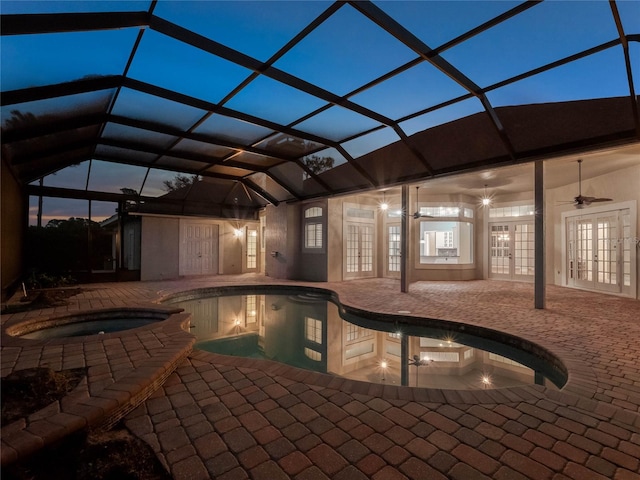 pool at dusk with an in ground hot tub, french doors, ceiling fan, glass enclosure, and a patio