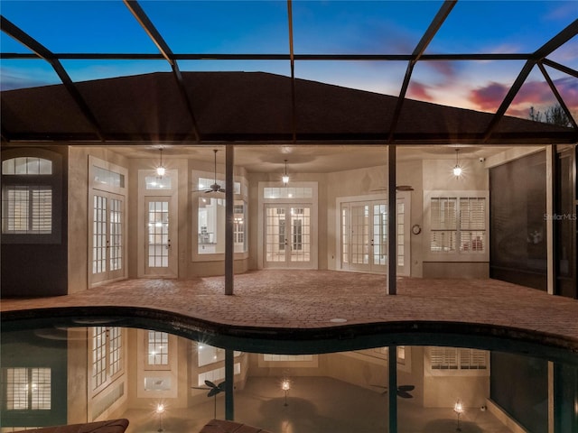 pool at dusk featuring ceiling fan, a lanai, a patio, and french doors