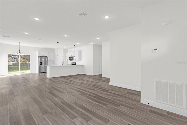 unfurnished living room with dark hardwood / wood-style flooring and an inviting chandelier