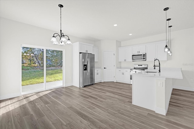 kitchen featuring stainless steel appliances, white cabinets, hanging light fixtures, and kitchen peninsula