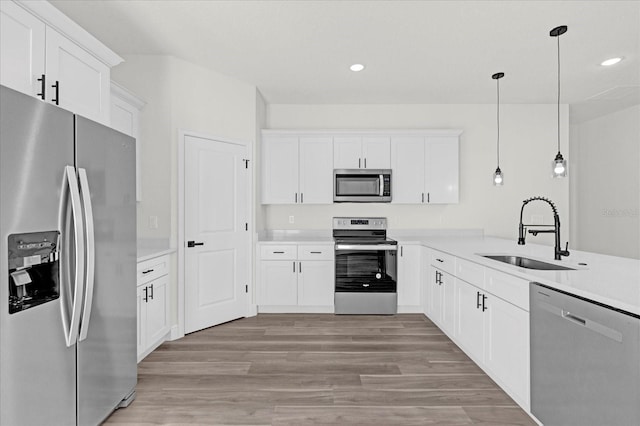 kitchen featuring kitchen peninsula, hanging light fixtures, stainless steel appliances, white cabinets, and sink