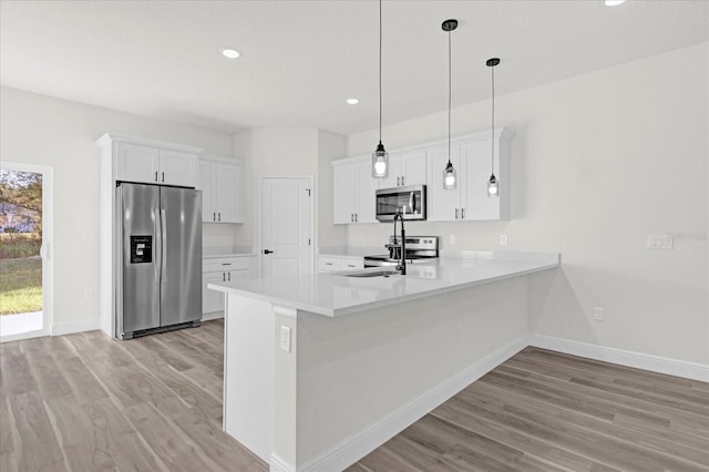 kitchen with stainless steel appliances, white cabinetry, kitchen peninsula, and pendant lighting