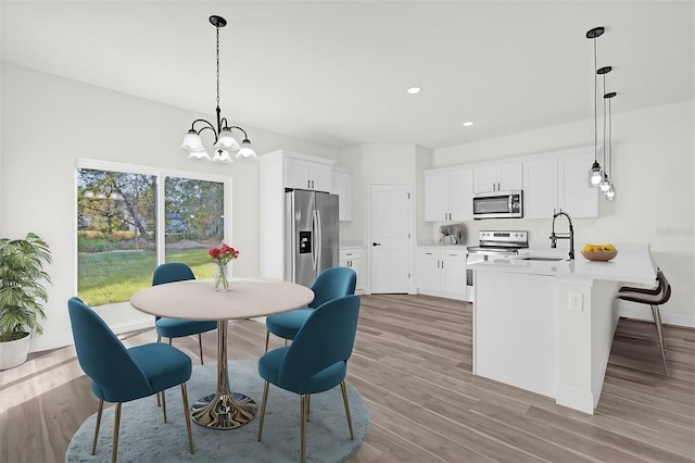 dining space with light hardwood / wood-style floors, a chandelier, and sink