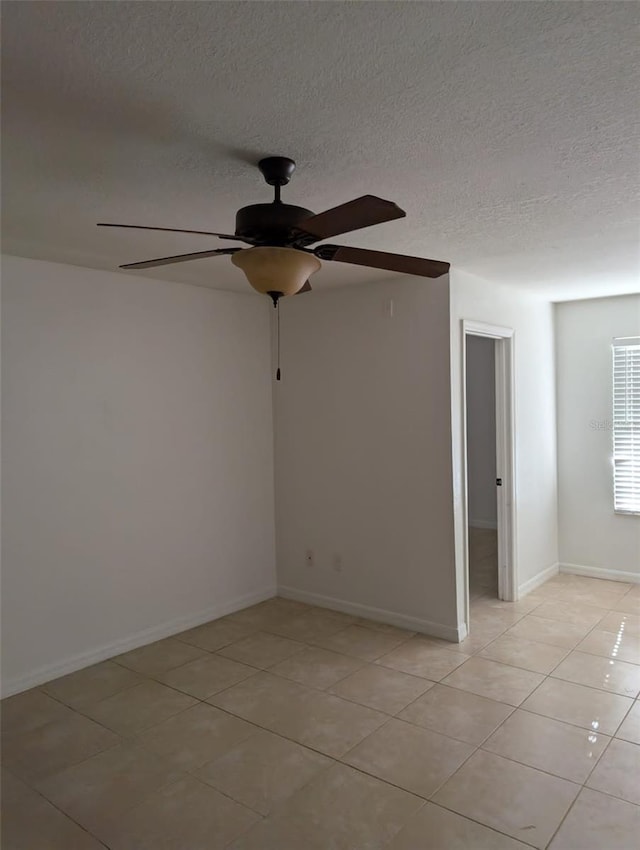 empty room with light tile patterned floors, a textured ceiling, and ceiling fan