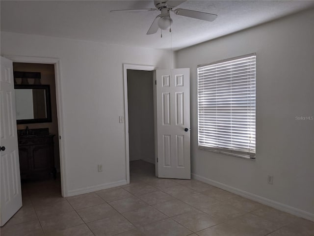 unfurnished bedroom featuring a spacious closet, ceiling fan, sink, a closet, and light tile patterned floors