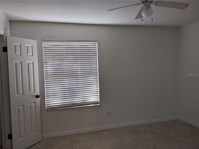 tiled spare room with a textured ceiling and ceiling fan