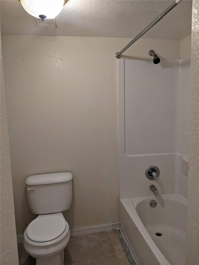 bathroom with tile patterned flooring, toilet, shower / tub combination, and a textured ceiling