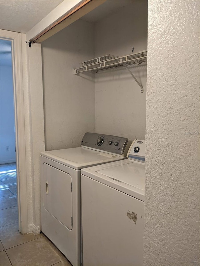 washroom with washer and clothes dryer, light tile patterned floors, and a textured ceiling