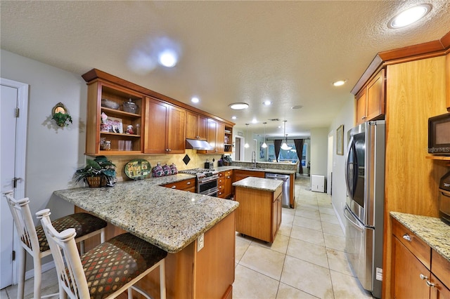 kitchen with a center island, sink, stainless steel appliances, a kitchen breakfast bar, and kitchen peninsula