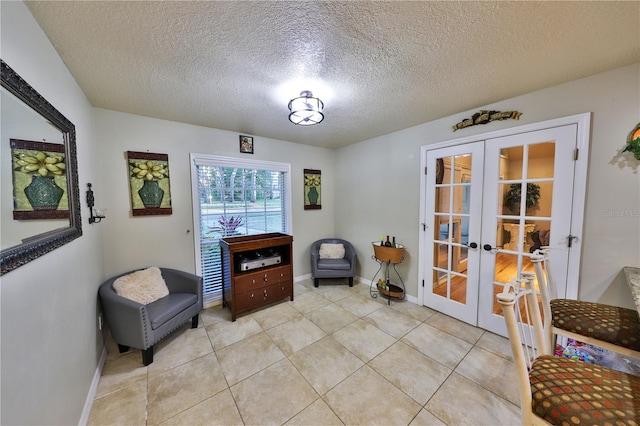 living area with light tile patterned flooring, a textured ceiling, and french doors