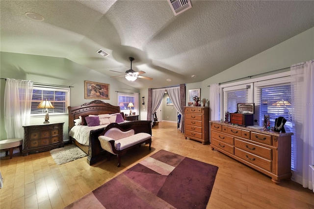 bedroom featuring a textured ceiling, ceiling fan, light hardwood / wood-style flooring, and vaulted ceiling