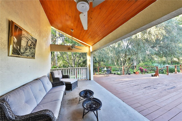 wooden terrace featuring ceiling fan and an outdoor living space with a fire pit