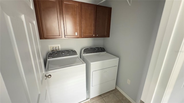 clothes washing area with cabinets, separate washer and dryer, and light tile patterned floors