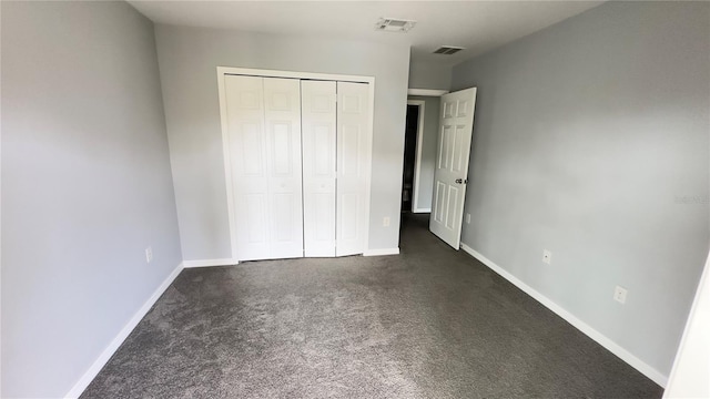 unfurnished bedroom with a closet and dark colored carpet