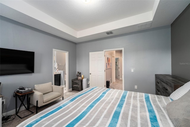 bedroom featuring a textured ceiling, light colored carpet, and ensuite bathroom