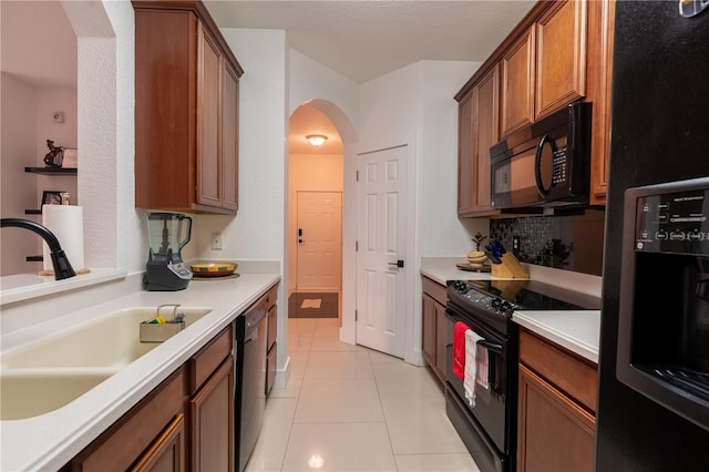 kitchen with black appliances, light tile patterned floors, sink, and a textured ceiling