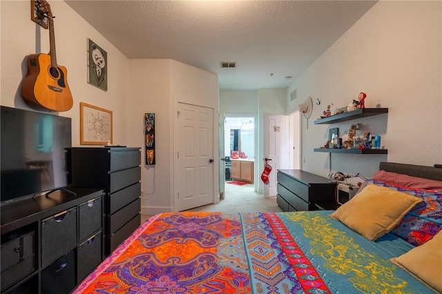 carpeted bedroom with ensuite bathroom and a textured ceiling