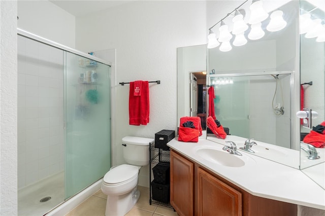 bathroom featuring tile patterned flooring, vanity, a shower with door, and toilet