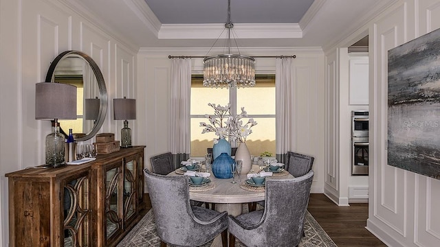 dining room with a raised ceiling, crown molding, dark wood-type flooring, and an inviting chandelier