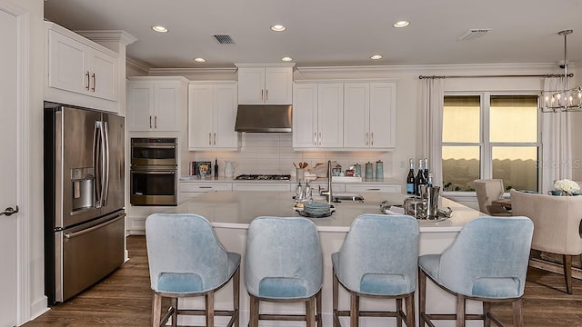 kitchen with stainless steel appliances, ventilation hood, decorative light fixtures, a center island with sink, and white cabinets