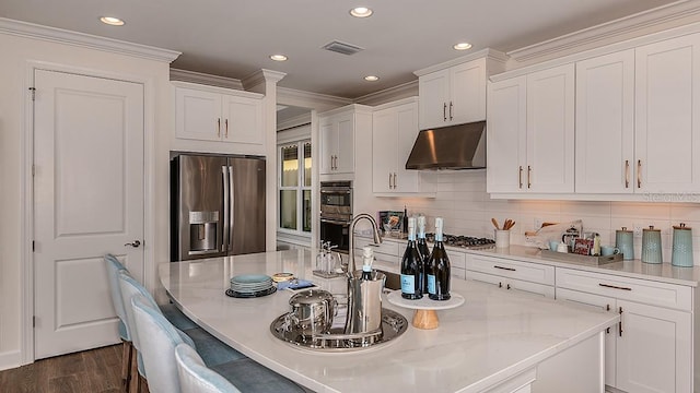 kitchen featuring white cabinets, light stone countertops, ornamental molding, stainless steel appliances, and extractor fan