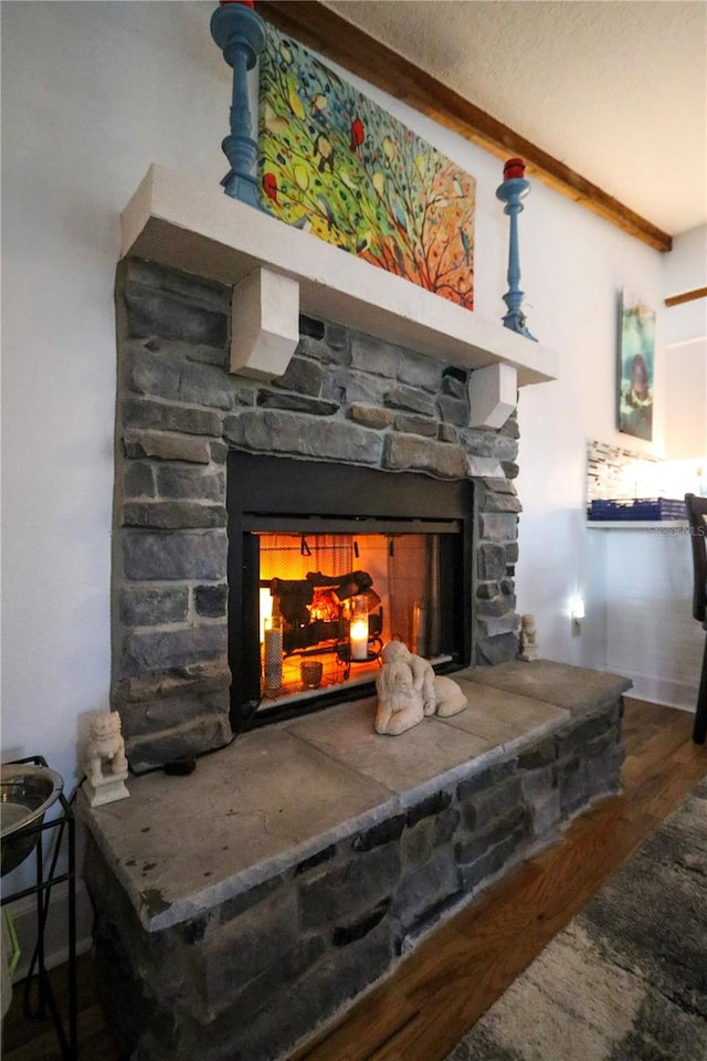 interior details with beamed ceiling, wood-type flooring, and a stone fireplace