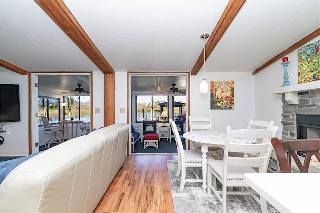 living room featuring a fireplace, light hardwood / wood-style floors, a textured ceiling, and a wealth of natural light