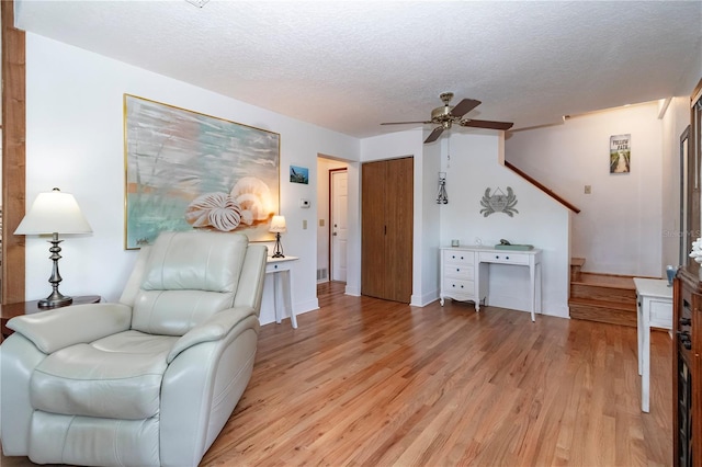 living area featuring ceiling fan, a textured ceiling, and light wood-type flooring