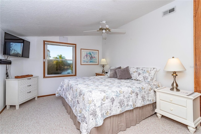 bedroom with light colored carpet, ceiling fan, vaulted ceiling, and a textured ceiling