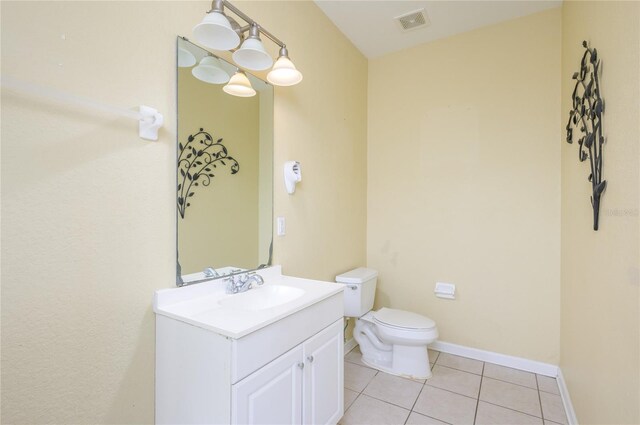 bathroom with toilet, vanity, and tile patterned floors