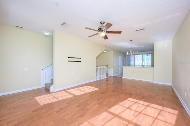 unfurnished room with ceiling fan with notable chandelier and light wood-type flooring