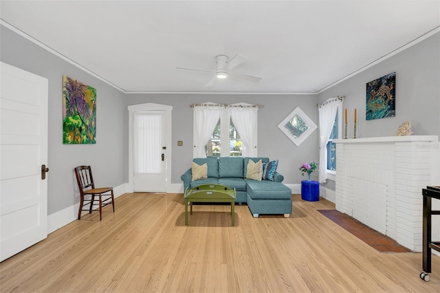 living room with ceiling fan, a fireplace, light wood-type flooring, and crown molding