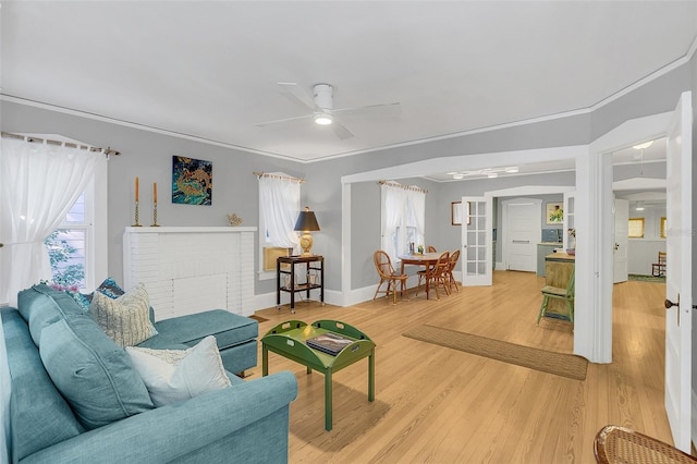 living room featuring a fireplace, ceiling fan, hardwood / wood-style floors, and crown molding